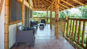 A covered outdoor seating area with wicker furniture and a bamboo railing. - Seaside Escape | Entire House | Pool Access (Manzanillo)