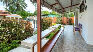 A covered outdoor dining area with a long table and benches, surrounded by greenery and a view of the outdoors. - Poolside | 2BR Home | Walk to Beach & Dining (Manzanillo)