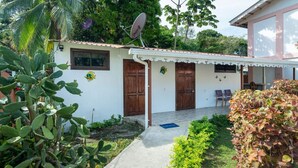 A white building with a satellite dish, two wooden doors, and a small porch area. - Poolside | 2BR Home | Walk to Beach & Dining (Manzanillo)