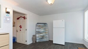 Eine kleine Küche mit einem weißen Kühlschrank, einem Holzschrank und einer dekorativen Vase.