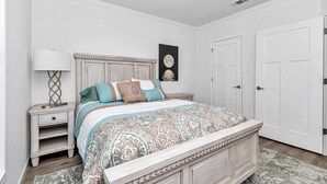 Une chambre à coucher avec un lit, des tables de chevet, une lampe et une porte.
