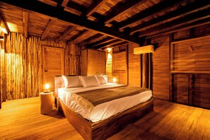 Un dormitorio tipo cabaña de madera con una cama grande, paredes de madera y techo inclinado.