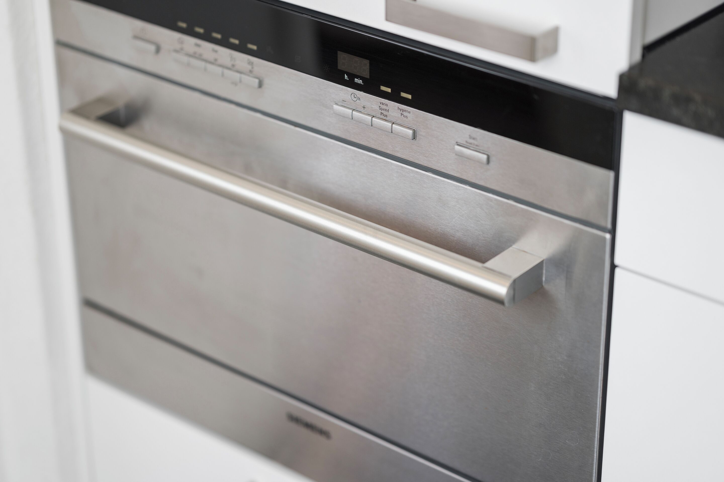 A stainless steel oven with a digital display and control panel in a modern kitchen.