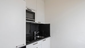 Una cocina moderna con armarios blancos, encimera negra y microondas integrado.