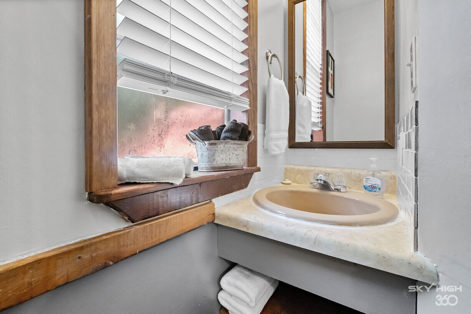 A bathroom with a window, a sink, and a mirror.