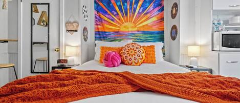 A bedroom with a bed, a nightstand, a wall clock, a mirror, and a door.