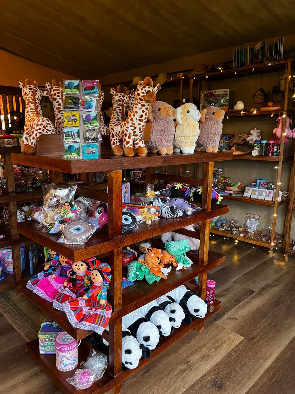 A multi-tiered wooden display shelf with various plush toys and items.