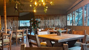 Un restaurante con mobiliario de madera, luces colgantes y amplios ventanales.