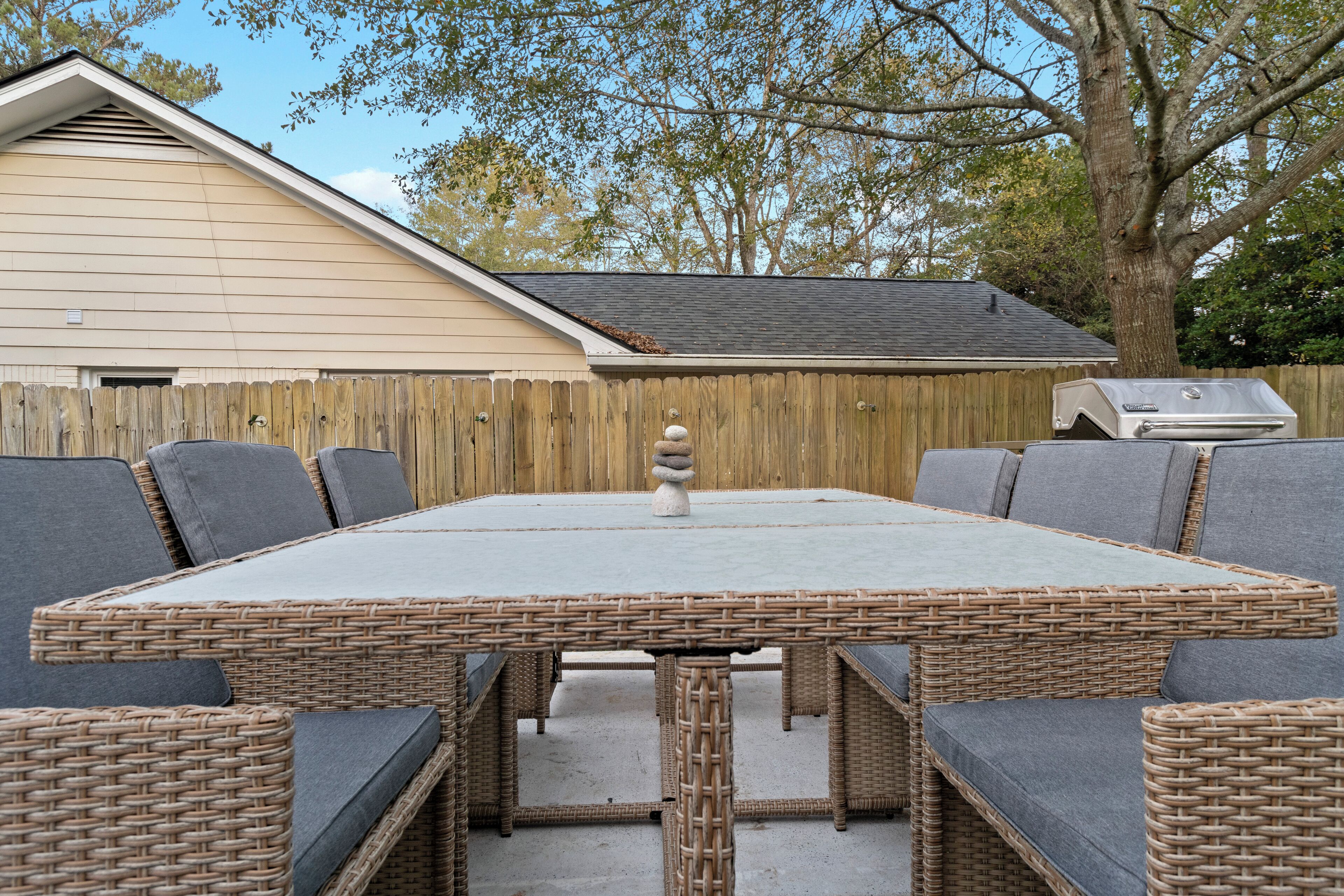 A large outdoor dining area with wicker furniture and grey cushions.