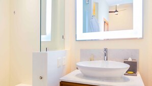 Een moderne badkamer met een groot ovaal wastafel, een spiegel en een wastafelmeubel met een houten kastje.