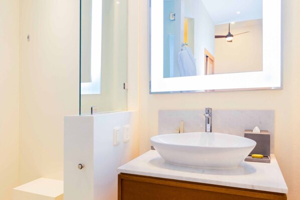 Un baño moderno con un lavamanos ovalado grande, un espejo y un mueble de tocador con un gabinete de madera.