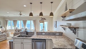 A modern kitchen with granite countertops, stainless steel appliances, and pendant lighting. - “Beach’d Pearl” Beach house with Private Beach and Pier in Ocean Springs (Ocean Springs)