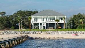 A two-story beach house with a covered porch, a staircase leading to the upper level, and a view of the ocean. - “Beach’d Pearl” Beach house with Private Beach and Pier in Ocean Springs (Ocean Springs)