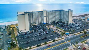 A high-rise hotel with multiple floors, a parking lot, and a view of the beach and ocean. - NEW! Tide's End Getaway (Panama City Beach)
