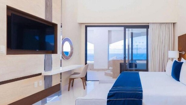 Une chambre d’hôtel avec un grand lit, un bureau, une chaise et un téléviseur fixé au mur.