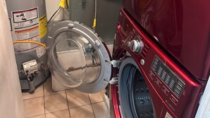 Un lavadero pequeño con una lavadora roja, un secador gris y un calentador de agua.