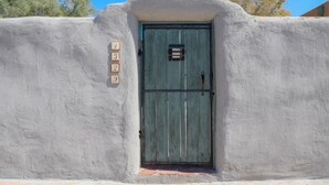 Un edificio rústico con fachada desgastada, una puerta verde y una pequeña ventana encima de la puerta.