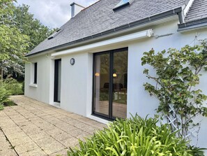 A modern house with a tiled roof, a large sliding glass door, and a small attached structure.