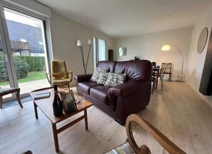 Relax in this stylish living room with a sofa, coffee table, and dining area leading to an outdoor space.