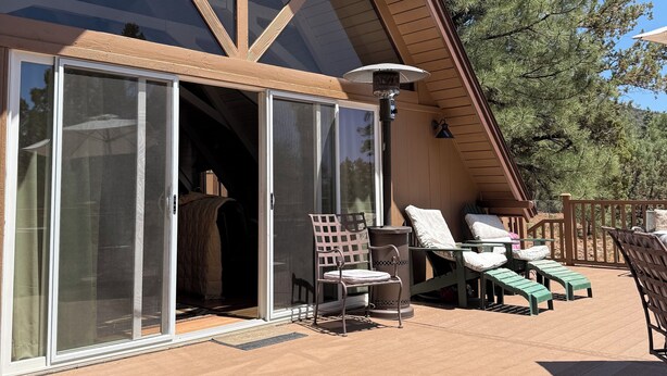 En moderne bygning med store glasdøre, en overdækket terrasse med udendørs møbler og en træterrasse.