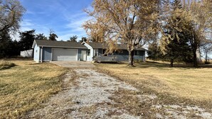 A single-story house with a garage, a covered porch, and a gravel driveway.