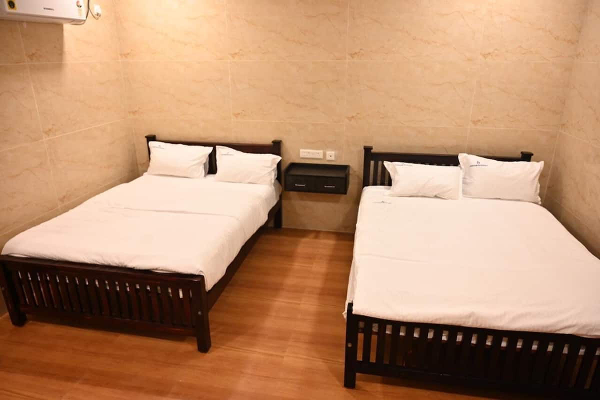 A room with two wooden beds, each with white bedding and pillows, a small bedside table, and a wall-mounted air conditioning unit.