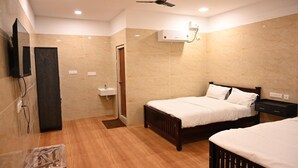 A hotel room with two beds, a ceiling fan, an air conditioning unit, a small sink, and a television mounted on the wall. - Thangam Residency (Tiruvannamalai)