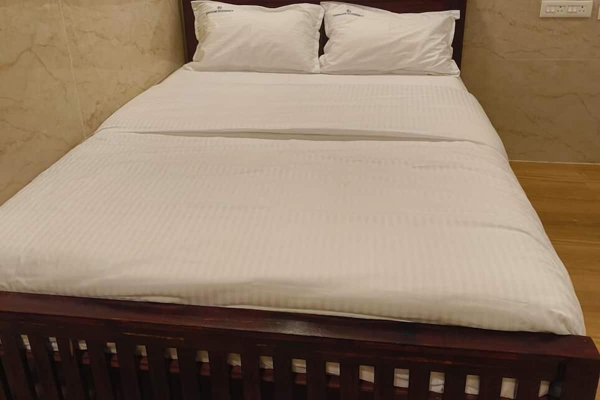 A neatly made bed with white bedding and wooden headboard in a room with marble walls.