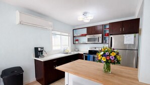 Una cocina moderna con armarios de madera oscura, electrodomésticos de acero inoxidable, una encimera de madera y un jarrón con flores.