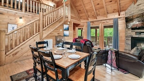 L’intérieur d’un chalet en bois comprend un coin repas, une cheminée et un escalier.