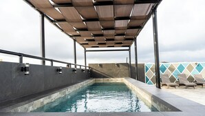 A rooftop pool with a wooden pergola, lounge chairs, and a geometric wall design. - HOTEL SOCRAM GH  (Cabo San Lucas)