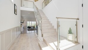 A spacious interior with a staircase leading to an upper level, a modern kitchen area, and a view of the outdoors. - Marvelous Home In Victoria, BC (Langford)
