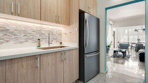 Een moderne keuken met houten kastjes, een roestvrijstalen koelkast en een betegelde spatwand.
