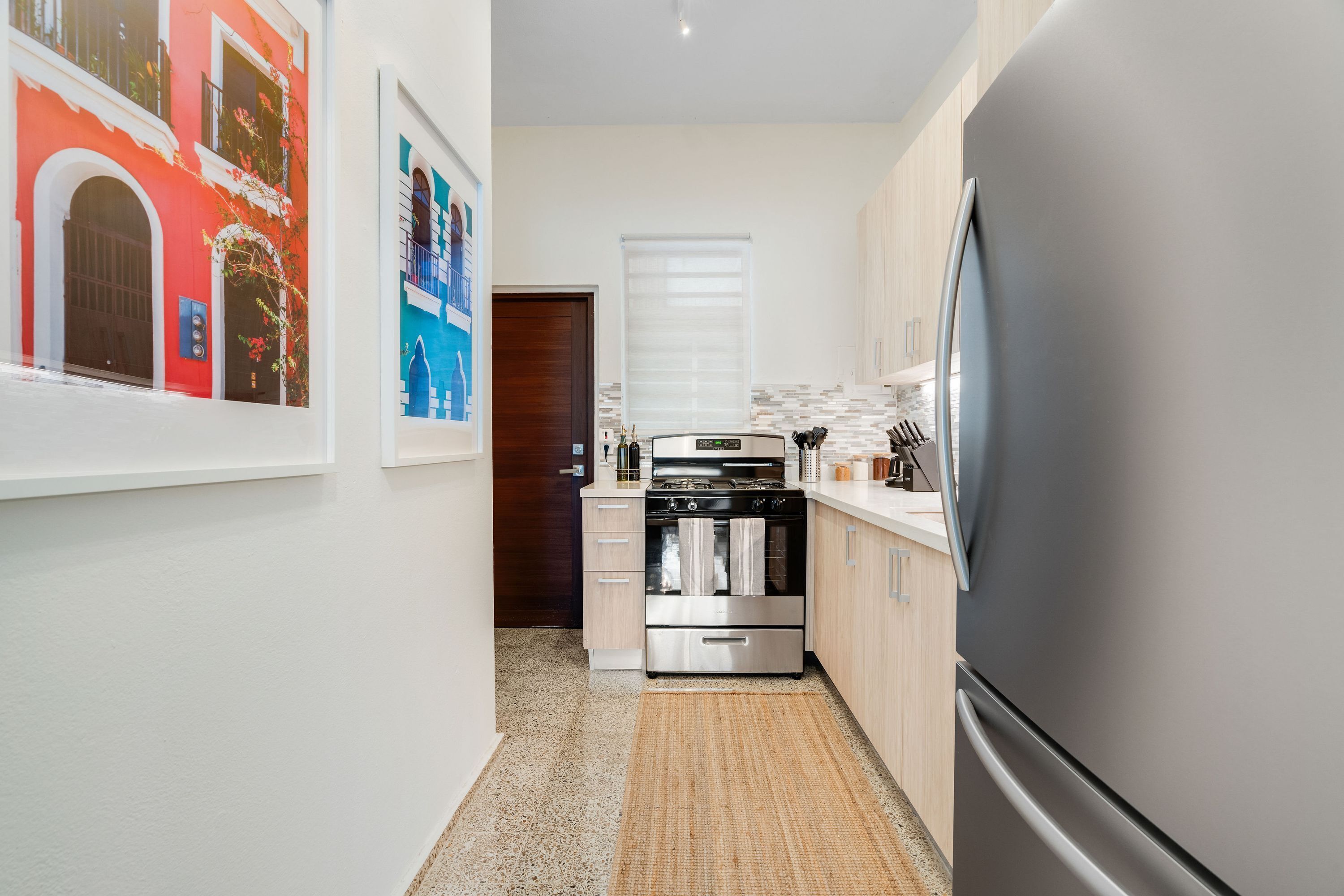 A compact kitchen with a stainless steel refrigerator, a built-in oven, and a small countertop.
