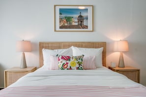 A neatly made bed with striped bedding, two bedside lamps, and a framed picture above it. - Stylish Apartment in Condado (San Juan)