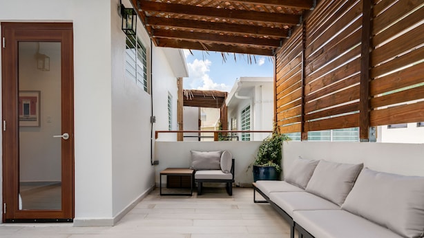 A balcony with a sofa, a small table, and a chair. - Stylish Apartment in Condado (San Juan)