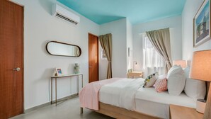 A bedroom with a bed, bedside table, lamp, and a window with curtains. - Stylish Apartment in Condado (San Juan)