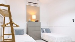 Ein Schlafzimmer mit zwei Betten, einem Kleiderschrank, einer Kleiderstange und einer Klimaanlage.