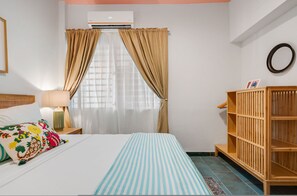 A hotel room with a bed, a wooden bookshelf, a window with curtains, and an air conditioning unit. - Chic Apartment Pool Parking in Central Condado (San Juan)