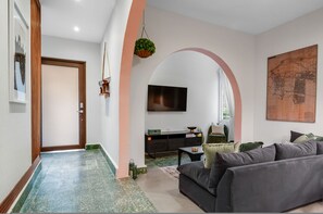 A modern living room with a grey sofa, a flat-screen TV, and a map on the wall. - Chic Apartment Pool Parking in Central Condado (San Juan)