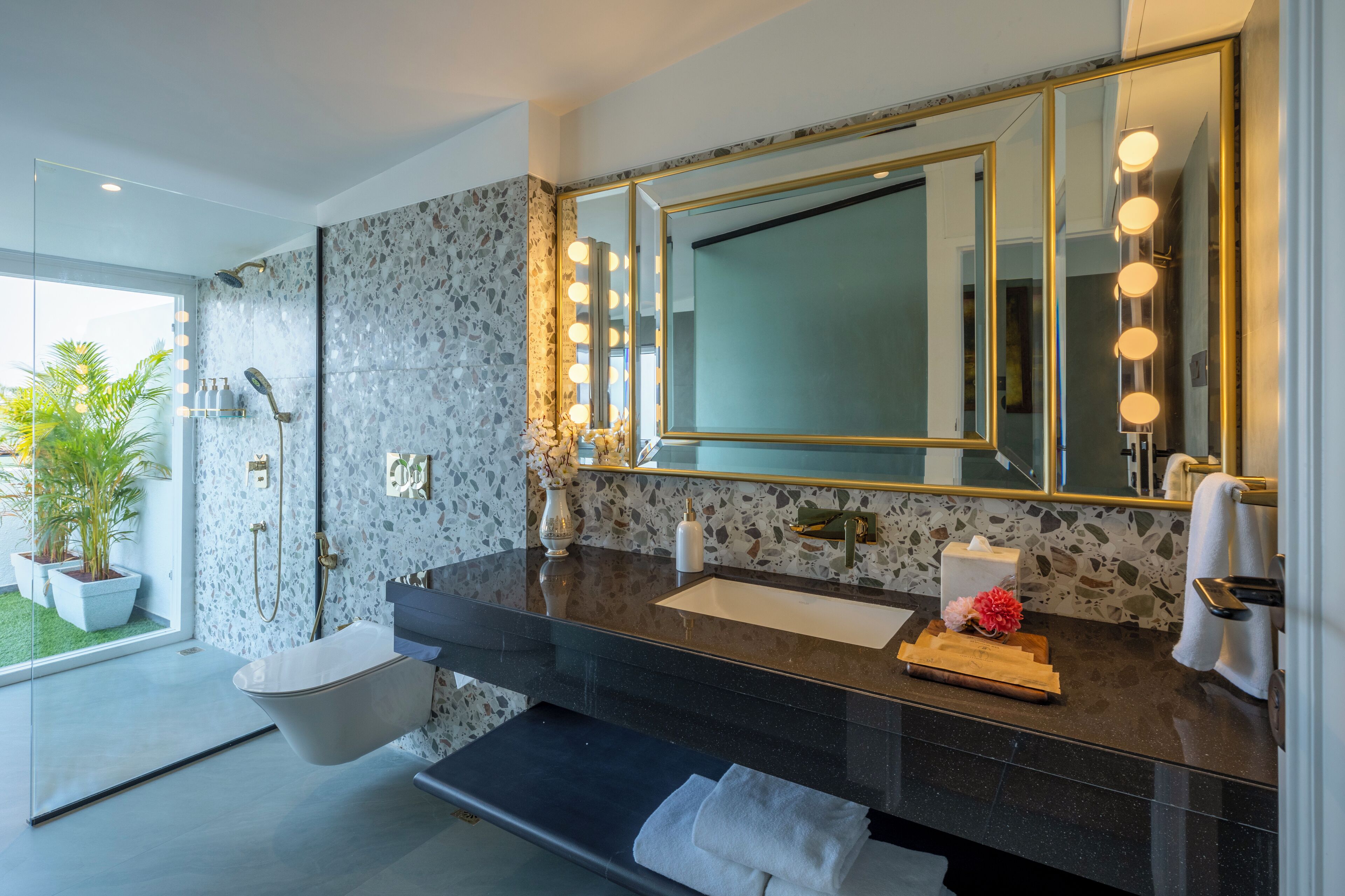 A modern bathroom with a freestanding bathtub, a large mirror with lights, a sink, and a shower area.