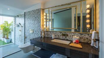 A modern bathroom with a freestanding bathtub, a large mirror with lights, a sink, and a shower area.