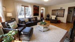 Ein Wohnzimmer mit Sofa, Sesseln, Couchtisch und Kamin.