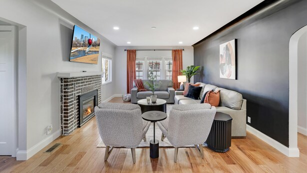 Una sala de estar moderna con chimenea, sofás grises, una mesa de centro y un televisor montado en la pared.