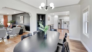 Una sala de estar moderna con una mesa de comedor de madera oscura, sofás grises y una pared de acento negra.