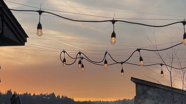 A hot tub in a rustic outdoor setting with string lights overhead. - Sunset Ridge, Near Downtown, Hot tub, Outdoor Living, all with Panoramic View,  (Spokane)