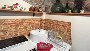 Eine Küche mit Ziegelwand, Holzbalkendecke und Regalen mit Küchenutensilien.
