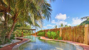 A wooden deck surrounding a circular pool with a wooden fence and palm trees.