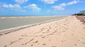 A beach with a clear sky, sandy shore, and footprints.