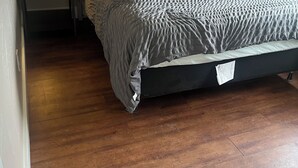 A single bed with a grey textured bedspread in a room with wooden flooring and a white headboard. - Charming bungalow with AC and WiFi in a private rural part of Billings.  (Billings)